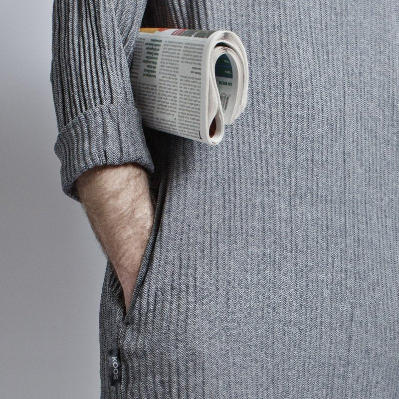 6. Close-up of KOOSdisain dress pocket with newspaper, highlighting black and gray fishbone pattern fabric