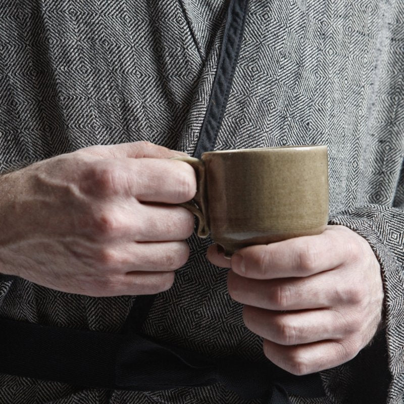 3. Close-up of hands holding cup in black fishbone pattern linen bathrobe