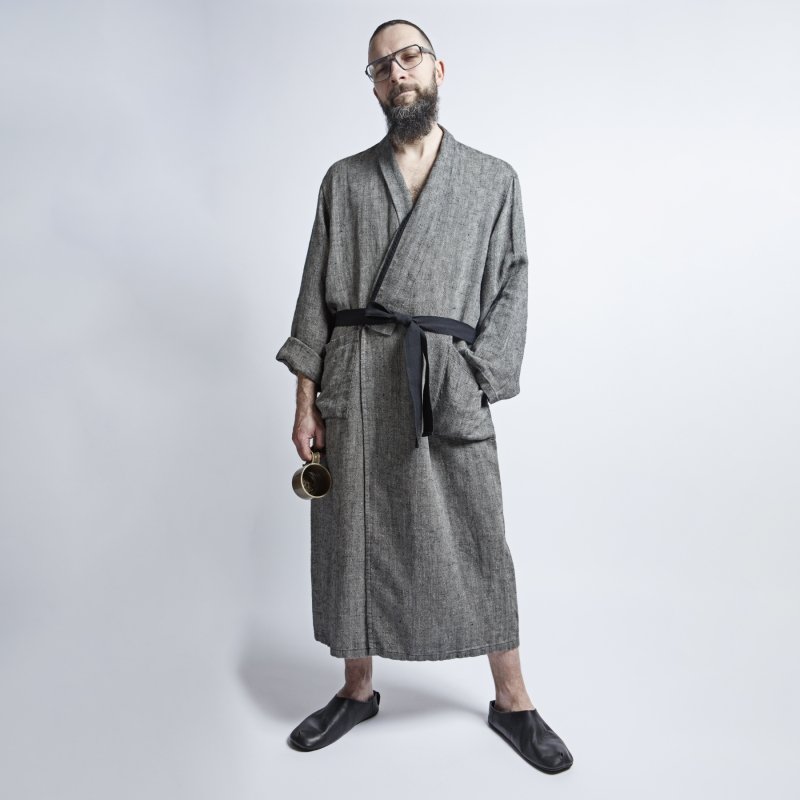 1. Man in black fishbone pattern linen bathrobe with black belt, holding a cup, in studio setting