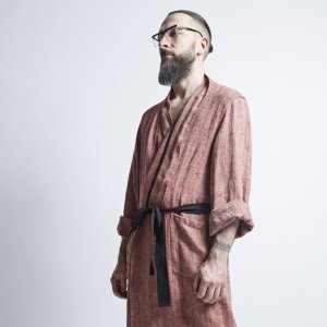 2. Side view of man in red fishbone pattern linen bathrobe with black belt, arms relaxed