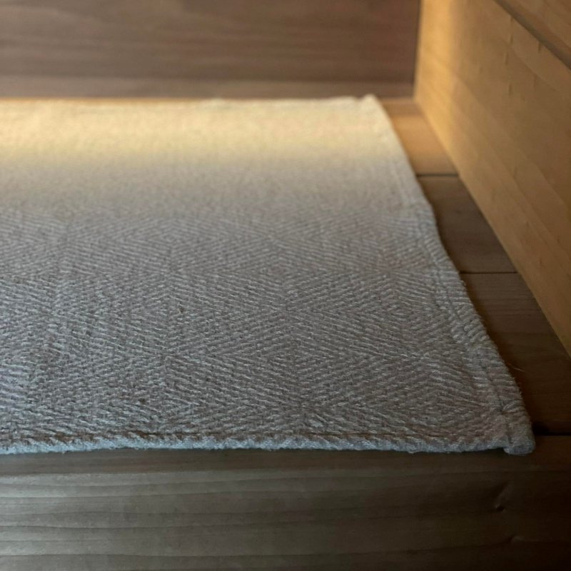 3. Close-up of beige linen sauna seat cover with fishbone pattern on wooden sauna bench