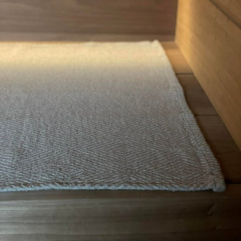 3. Close-up of beige linen sauna seat cover with fishbone pattern on wooden sauna bench