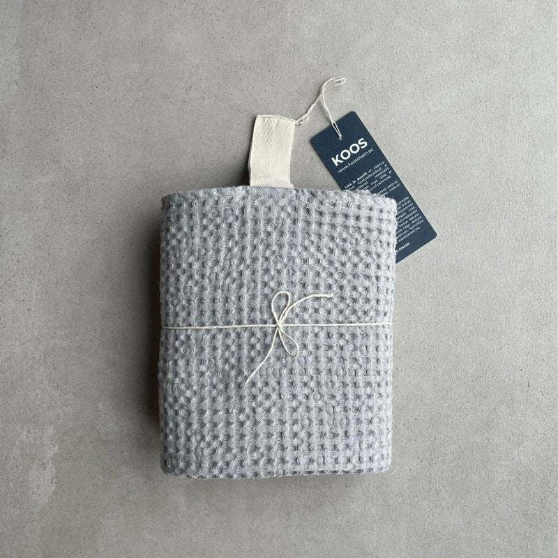 5. Rolled gray waffle fabric towel with white hanger and KOOSdisain tag, tied with string