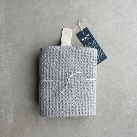 5. Rolled gray waffle fabric towel with white hanger and KOOSdisain tag, tied with string