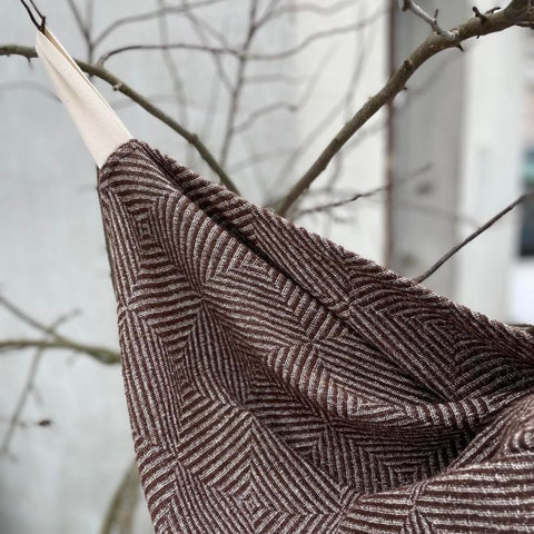 1. Brown linen towel with checkered fishbone pattern hanging on a branch outdoors