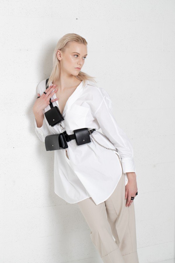1. Unisex leather body harness Kora No3 by PYKOK worn by female model in white shirt, showcasing adjustable belt and mini bags