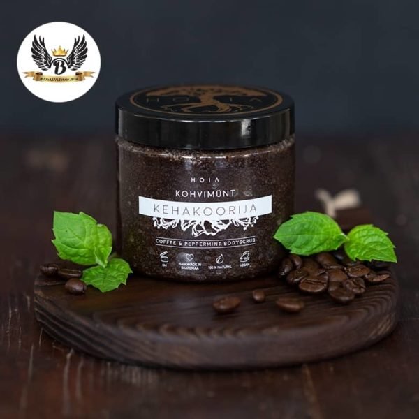1. HOIA homespa coffee and peppermint body scrub jar on wooden board with coffee beans and mint leaves
