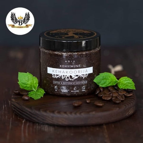 1. HOIA homespa coffee and peppermint body scrub jar on wooden board with coffee beans and mint leaves