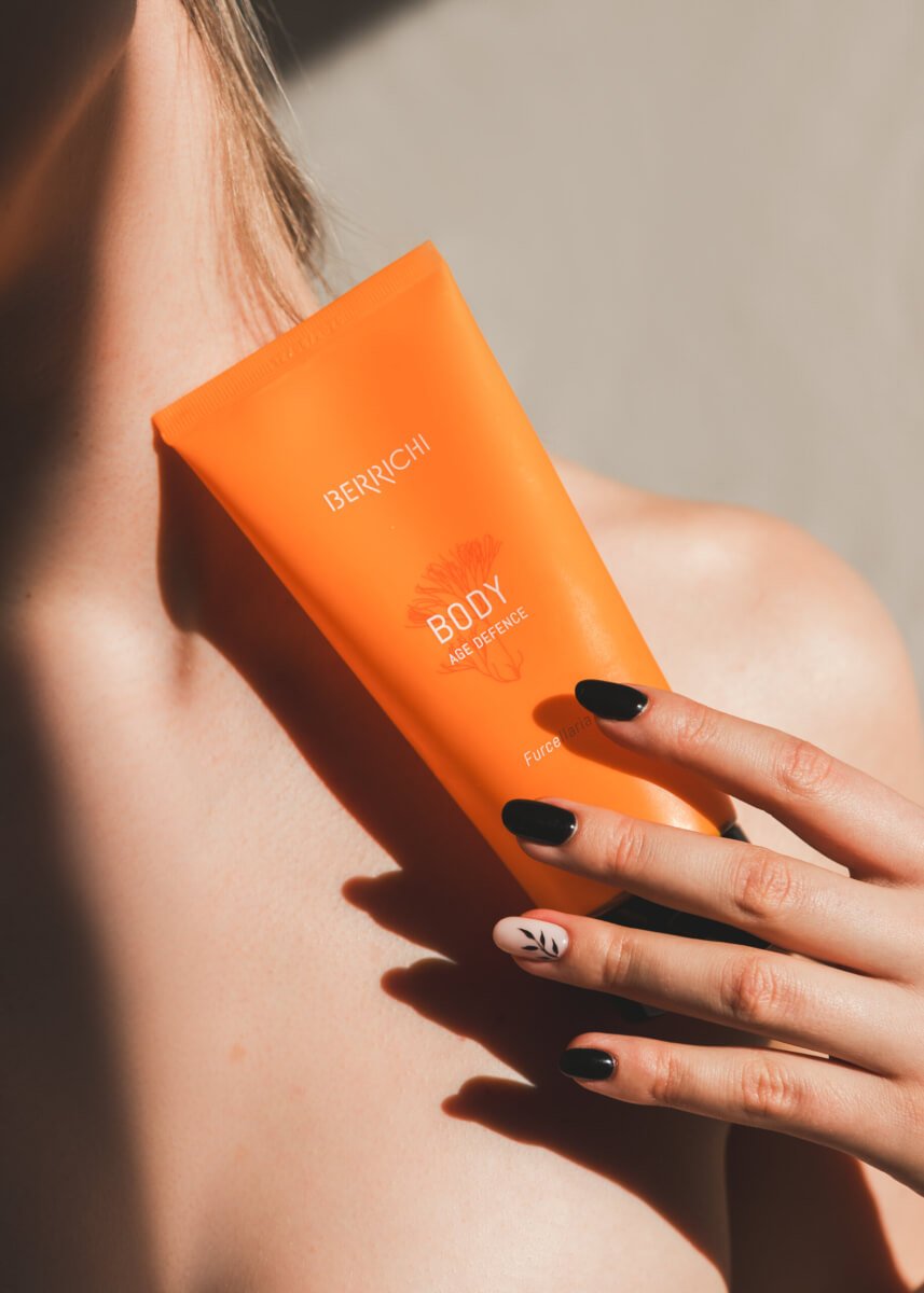 1. Woman holding Berrichi Age Defence BODY Cream, showcasing product on shoulder in lifestyle setting
