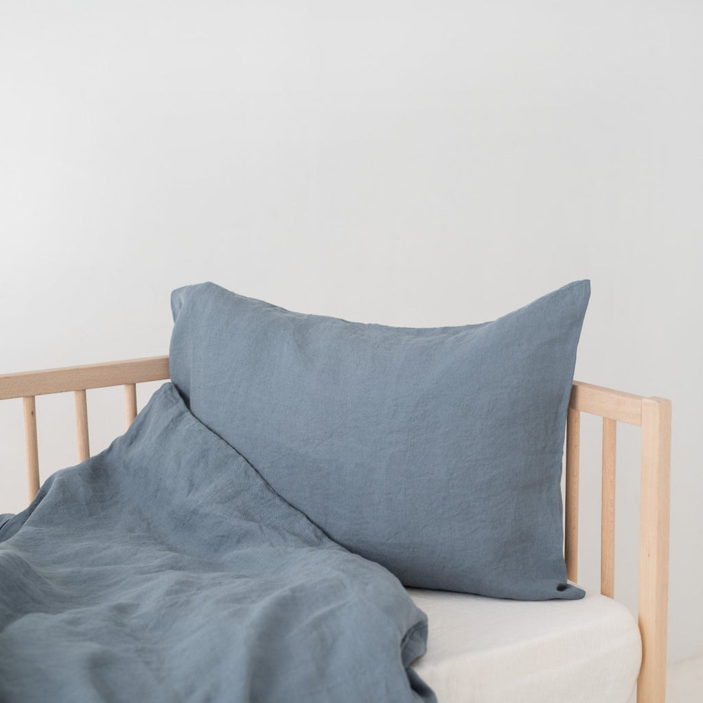 2. Blue fog linen pillow and duvet cover on a wooden crib, highlighting the soft and breathable fabric