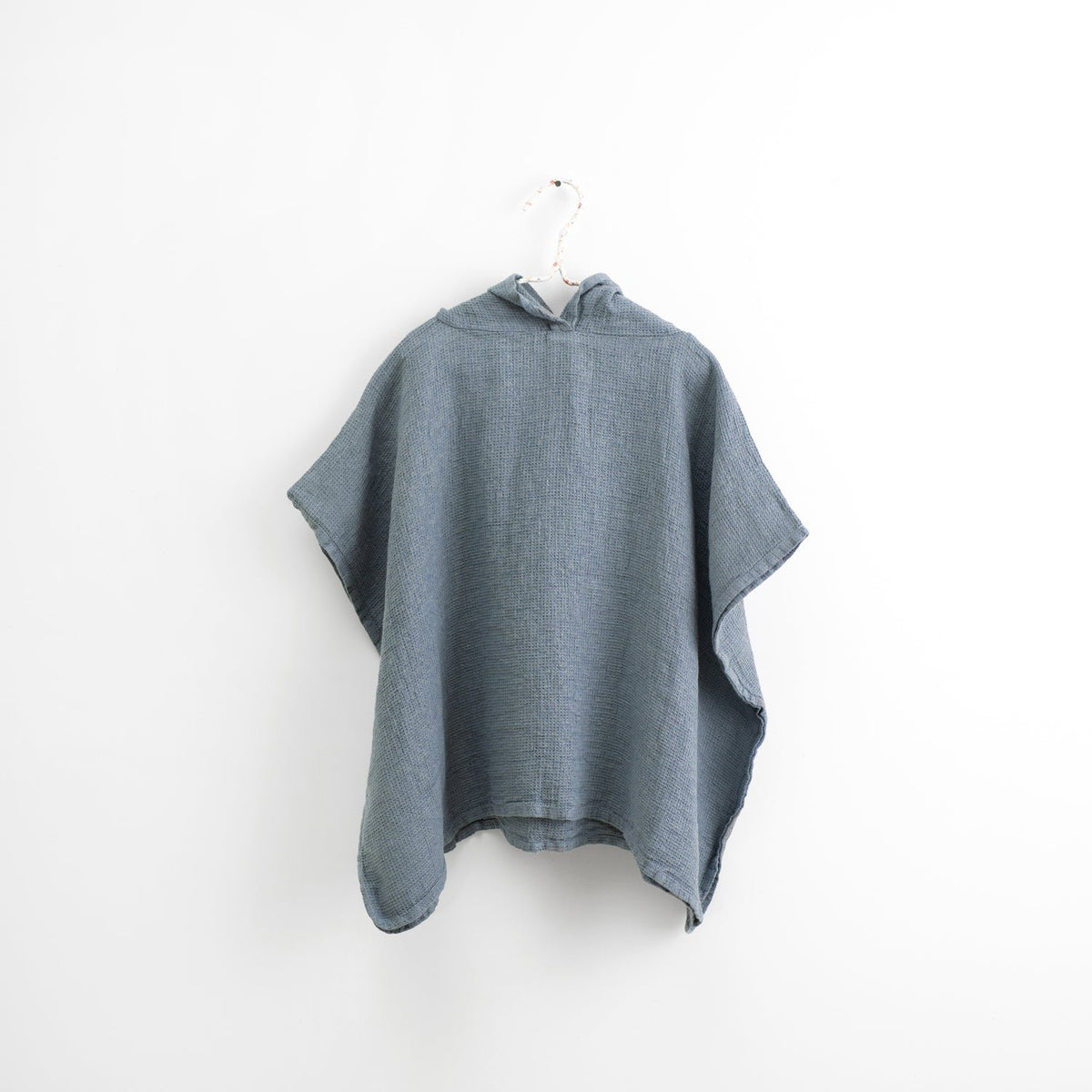 1. Kids' blue fog linen poncho with hood hanging on white background, showcasing fine waffle texture
