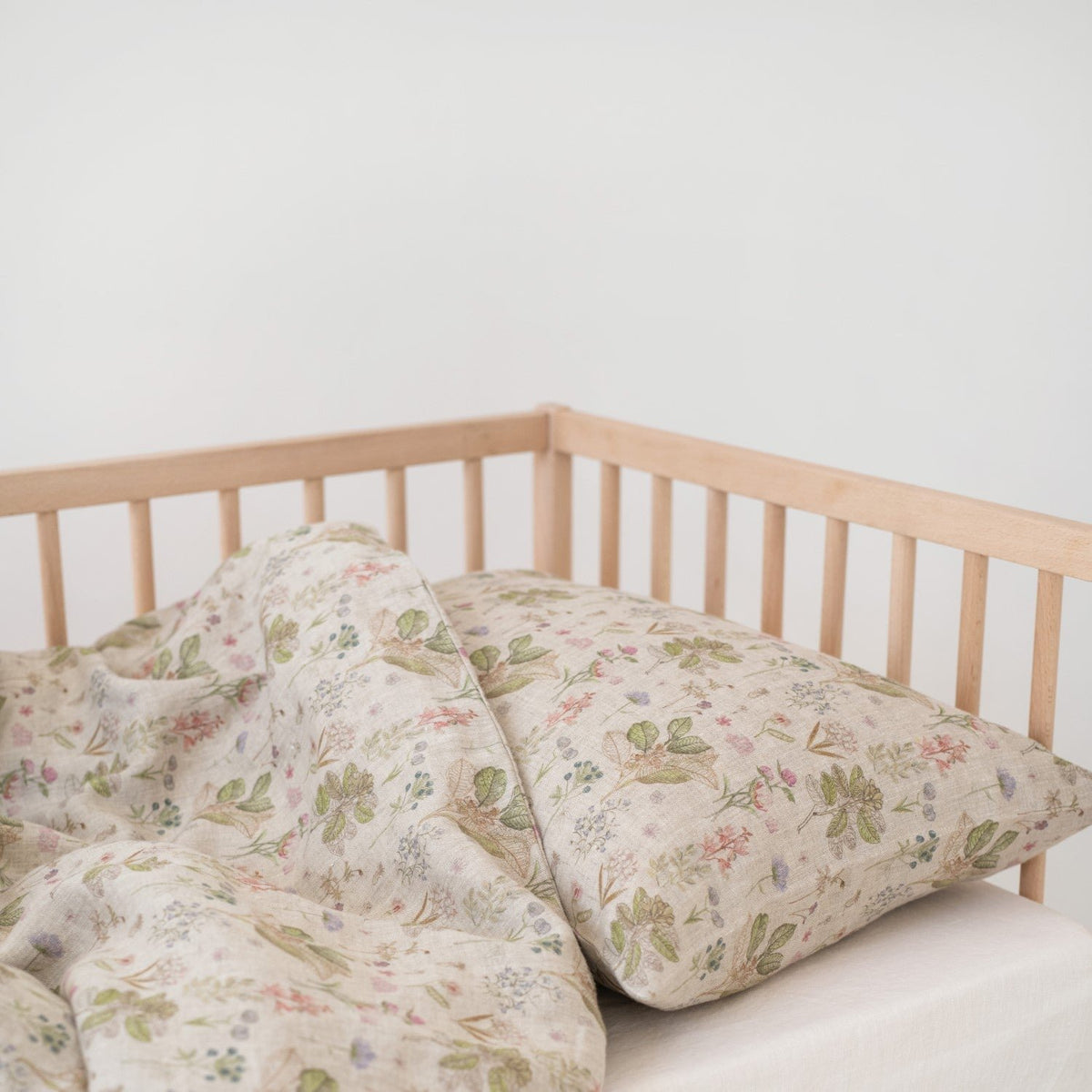 2. Botanical print linen duvet cover and pillowcase on kids' bed in wooden crib