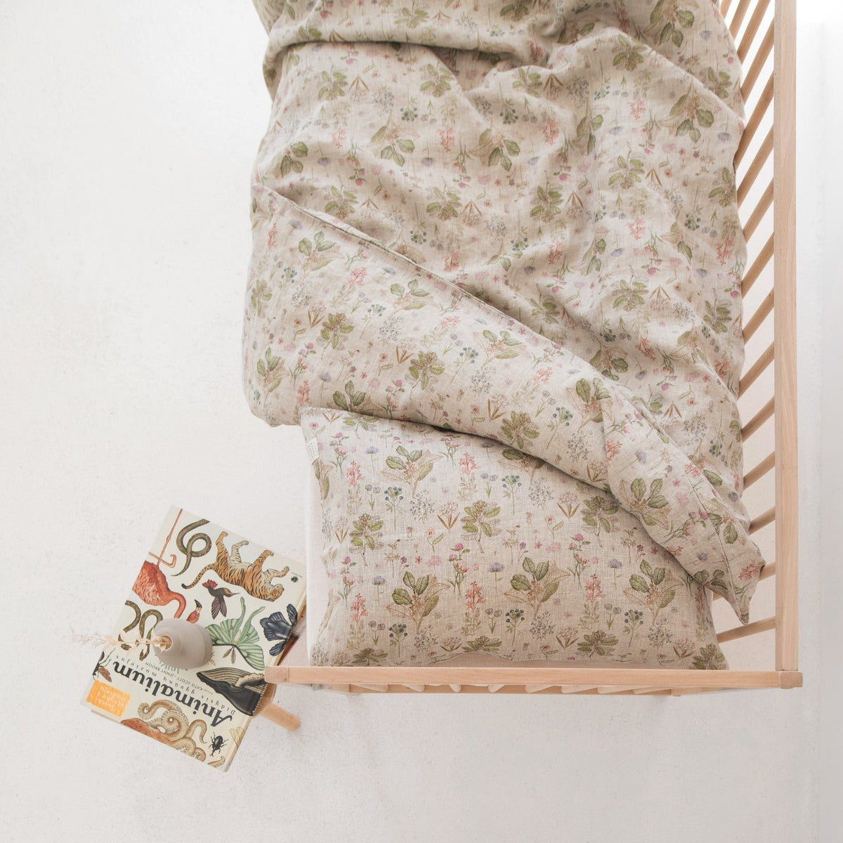 1. Top view of kids' bed with botanical print linen duvet cover set and book on side