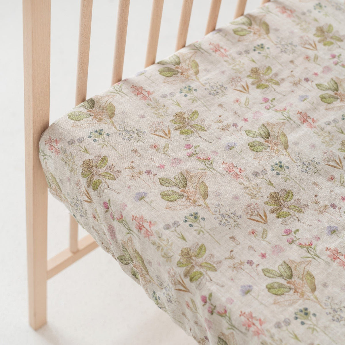 3. Close-up of kids sage linen fitted sheet with floral print on crib mattress