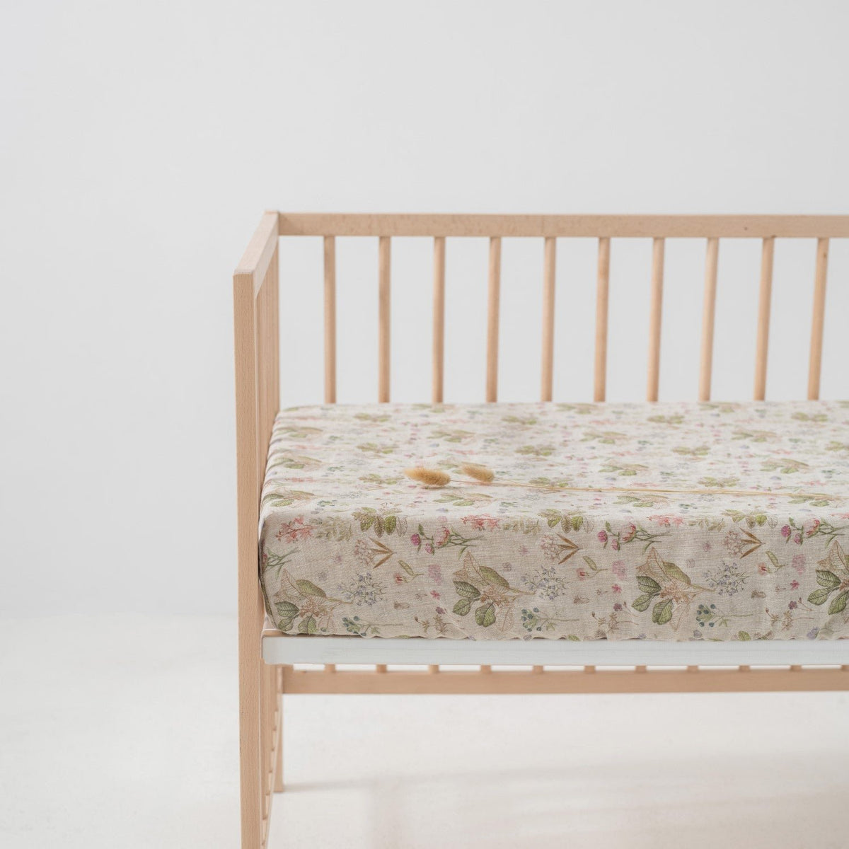 4. Kids sage linen fitted sheet with floral print on crib mattress in a minimalist nursery
