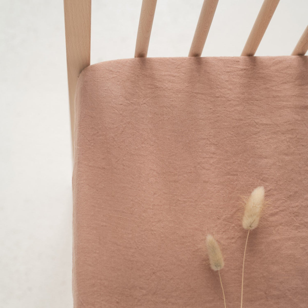 3. Close-up of cafe creme linen fitted sheet on crib corner, highlighting fabric texture and elastic fit