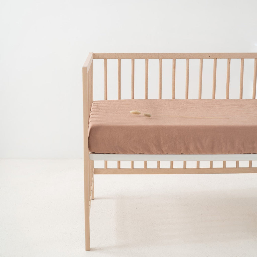 2. Cafe creme linen fitted sheet on crib in a bright room, emphasizing the snug fit and smooth surface