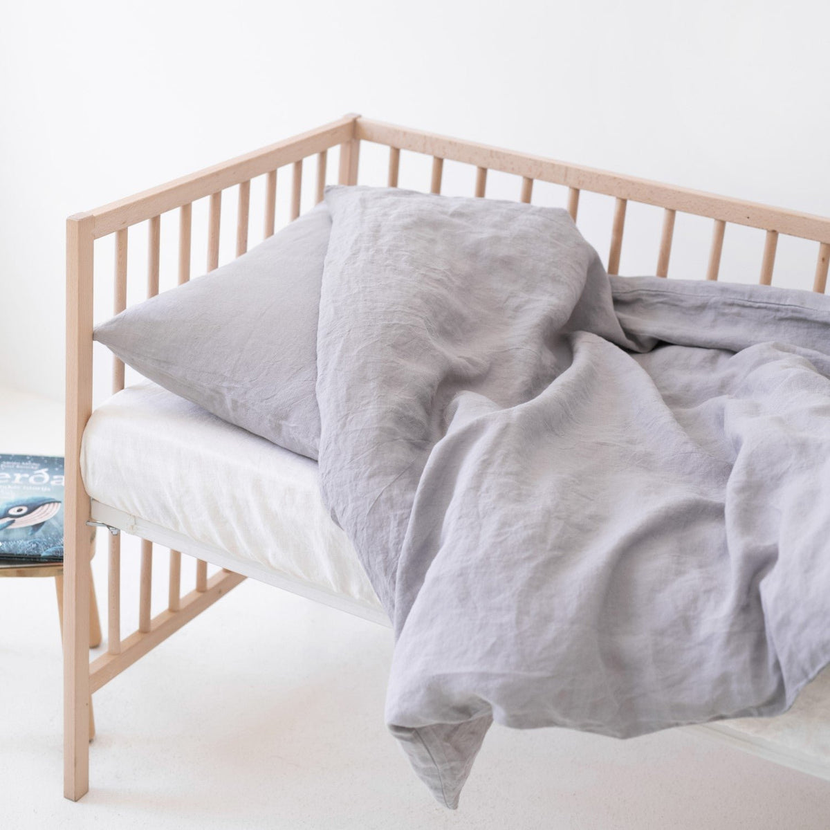 1. Light grey linen duvet cover set on a crib, highlighting the soft and breathable fabric in a children's room