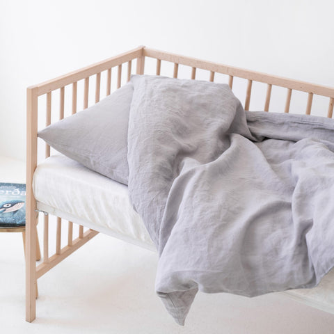 1. Light grey linen duvet cover set on a crib, highlighting the soft and breathable fabric in a children's room