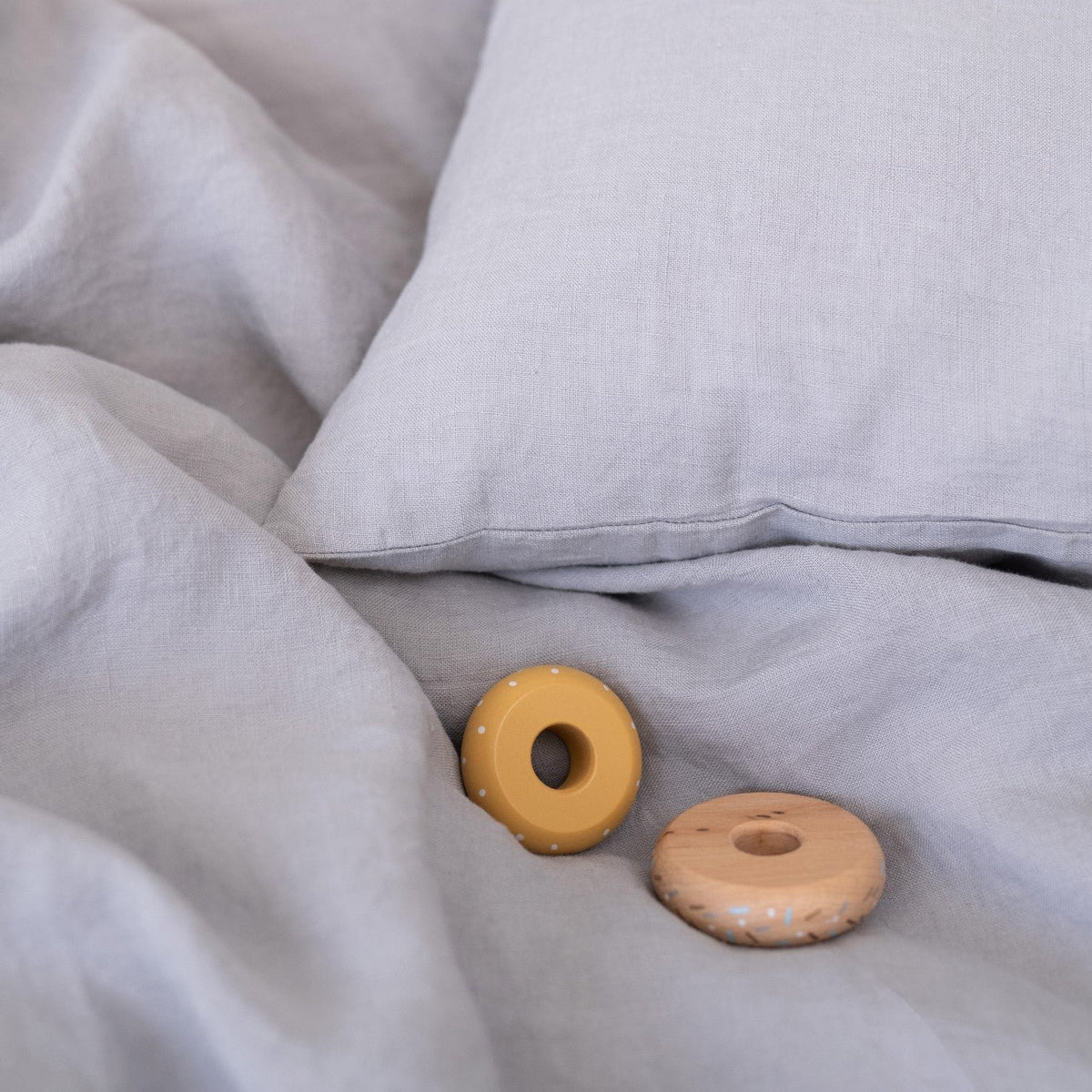 3. Close-up of light grey linen duvet cover with wooden toys, emphasizing soft texture and playful elements