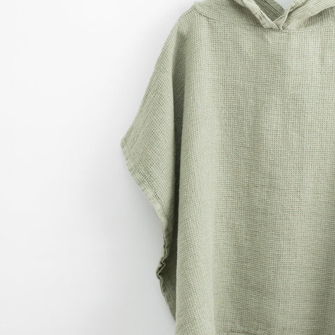 3. Close-up of sage green linen poncho showing fine waffle texture and hood detail