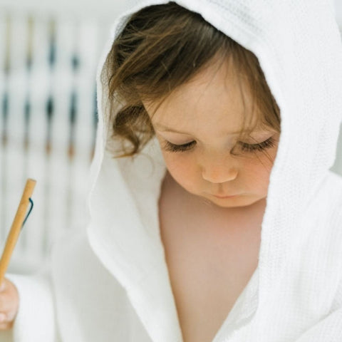 4. Close-up of child wearing white linen bathrobe with hood, focusing on face and fabric texture
