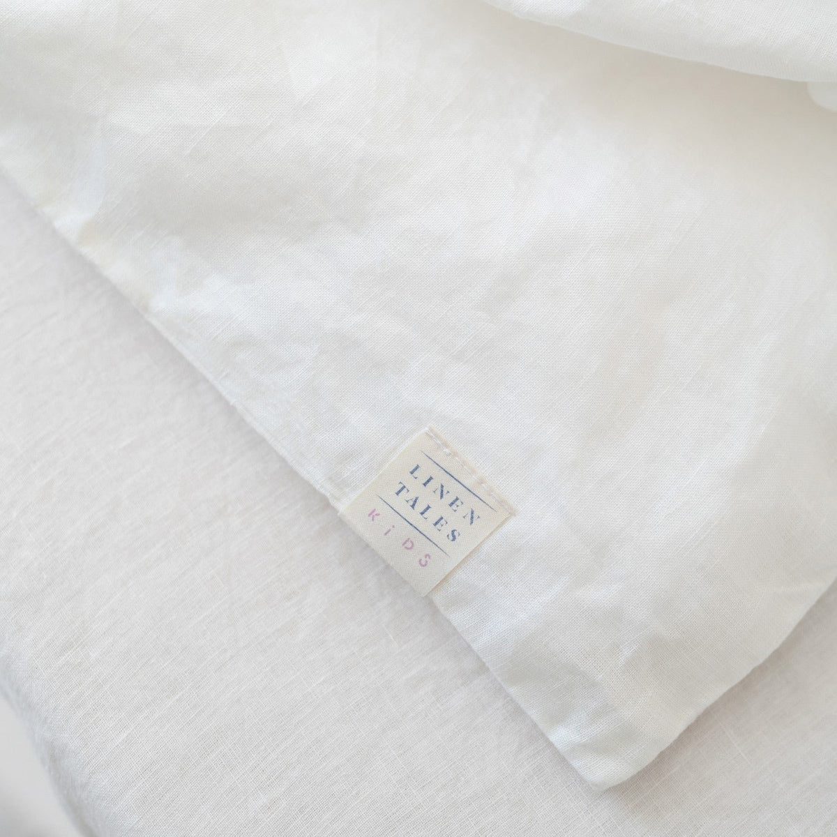 3. Close-up of Linen Tales brand label on white linen fabric