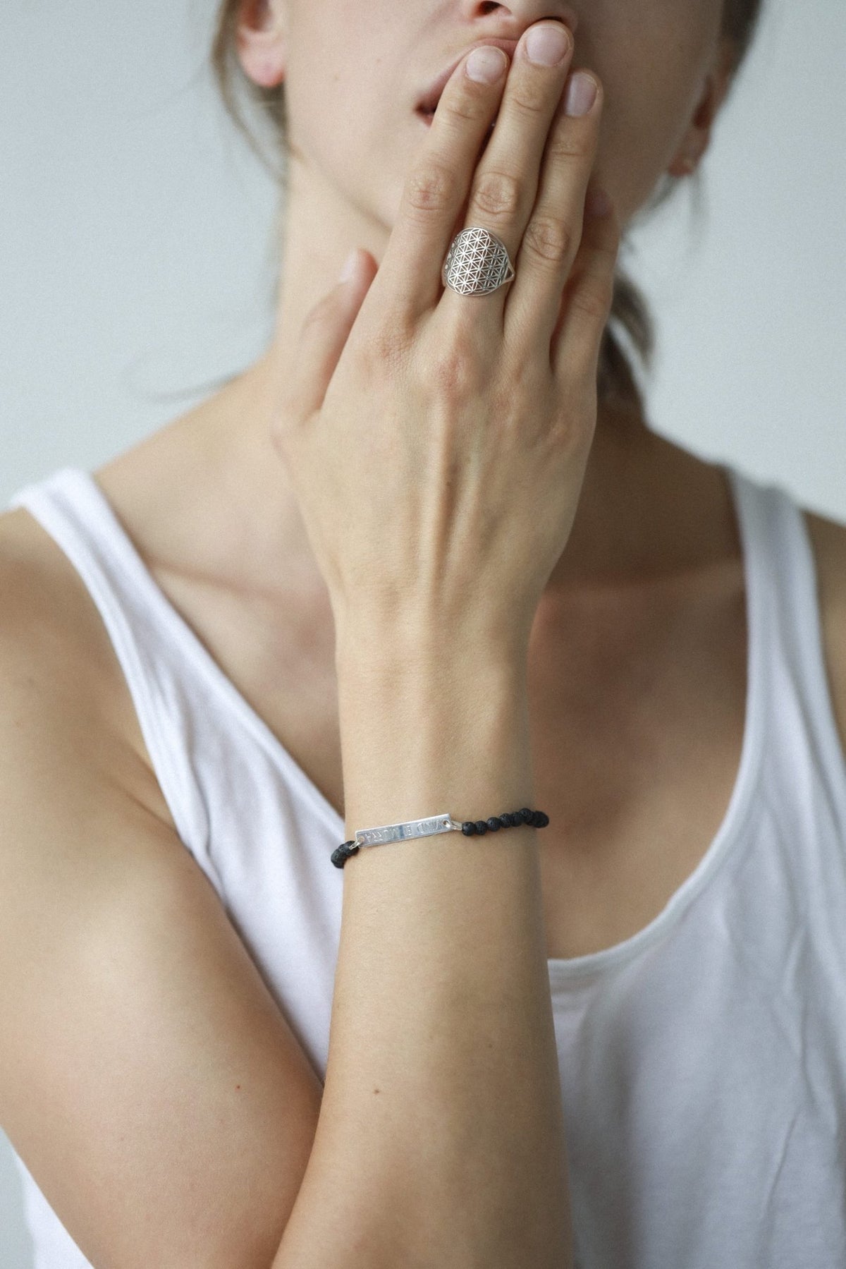 5. Close-up of woman wearing silver Flower Of Life Ring, paired with a black bracelet