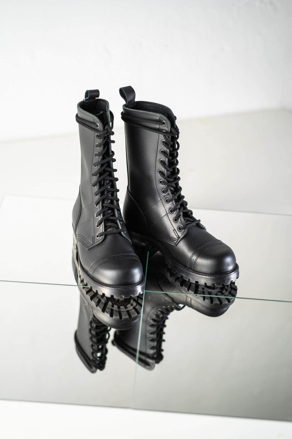6. Pair of Samelin 516 High Aviator Boots in black, reflected on glass surface, showcasing rugged sole