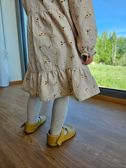 2. Child wearing Omaking yellow Mutsu slippers, standing by a window, highlighting breathable design