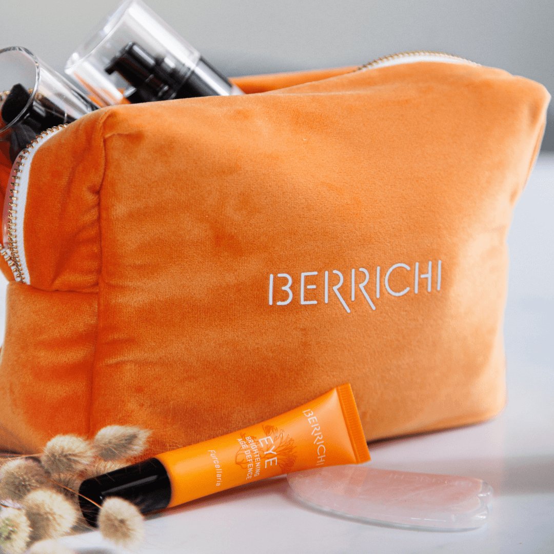 2. Close-up of Berrichi Cosmetic Bag in orange with logo, featuring beauty products