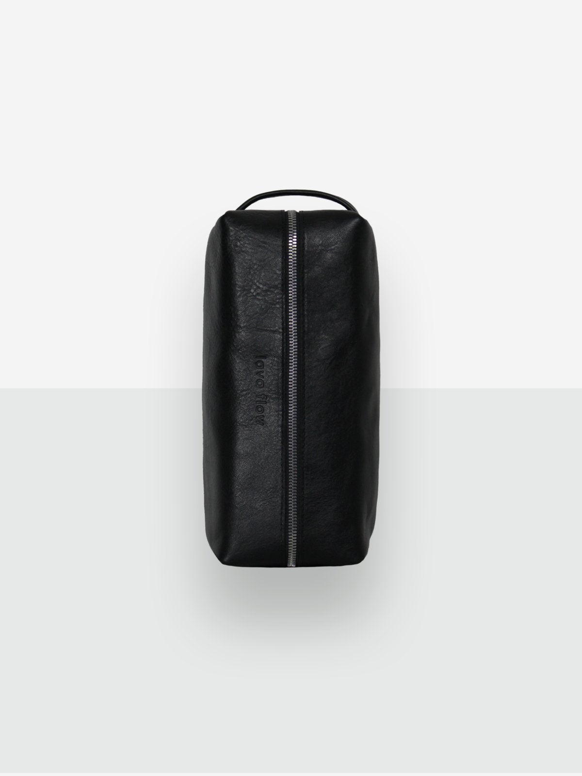 1. Studio shot of Lava flow VESUVIUS black cosmetic bag in Italian vegetable-tanned leather, showing zippered closure and handle