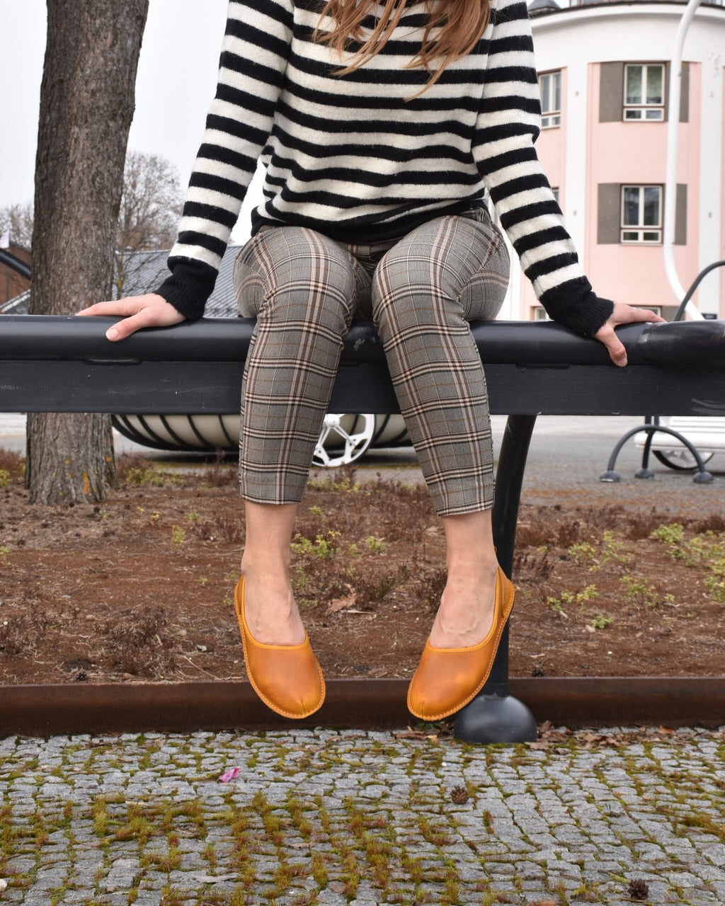 1. Woman wearing Omaking Kuutsid yellow leather shoes sitting on a bench in urban setting
