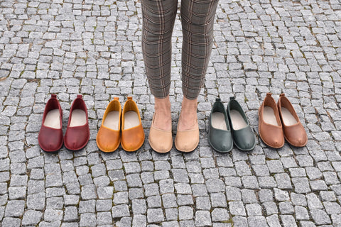 3. Woman standing on cobblestone with Omaking Kuutsid shoes in various colors, including dark green, red, and tan