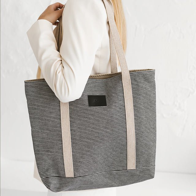 1. Woman holding Muni striped denim tote bag in lifestyle setting