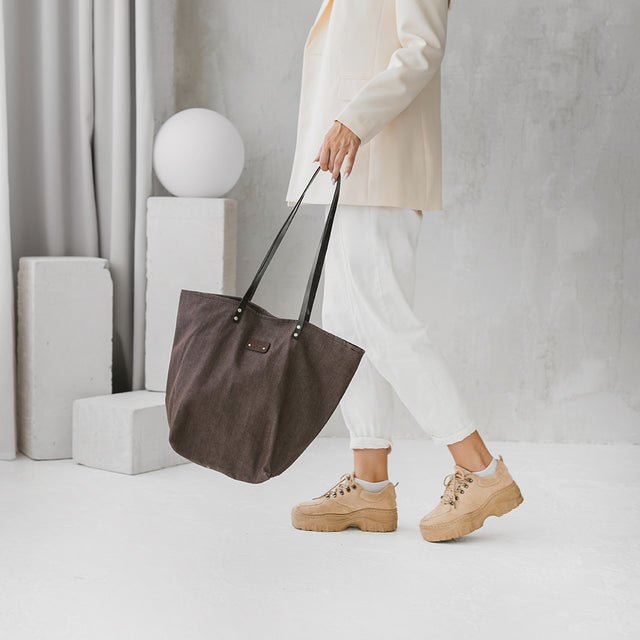 3. Woman walking with Muni brown denim tote bag, styled with casual outfit in a lifestyle setting