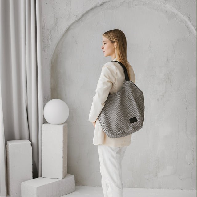 1. Woman wearing Muni striped linen tote bag in a minimalist setting