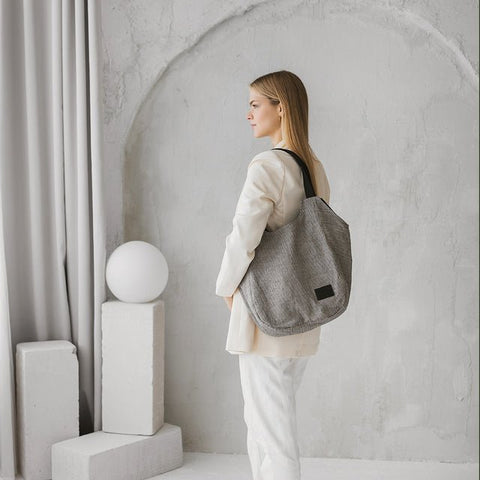 1. Woman wearing Muni striped linen tote bag in a minimalist setting