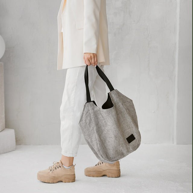 3. Woman holding Muni striped linen tote bag, shown in profile