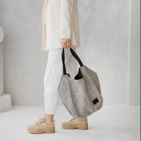 3. Woman holding Muni striped linen tote bag, shown in profile