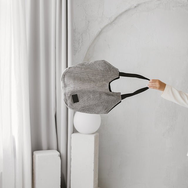 4. Muni striped linen tote bag held in a minimalist room