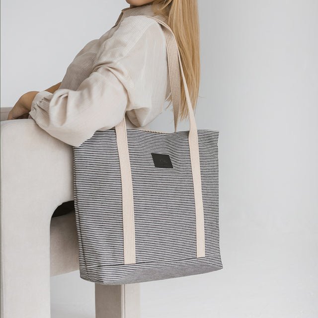 4. Woman seated with Muni striped denim tote bag in studio setting