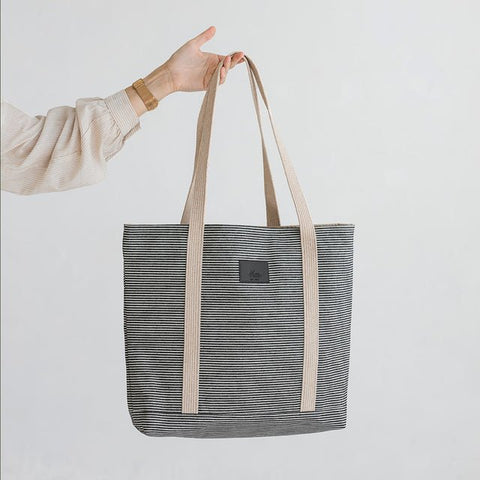 5. Hand holding Muni striped denim tote bag against white background