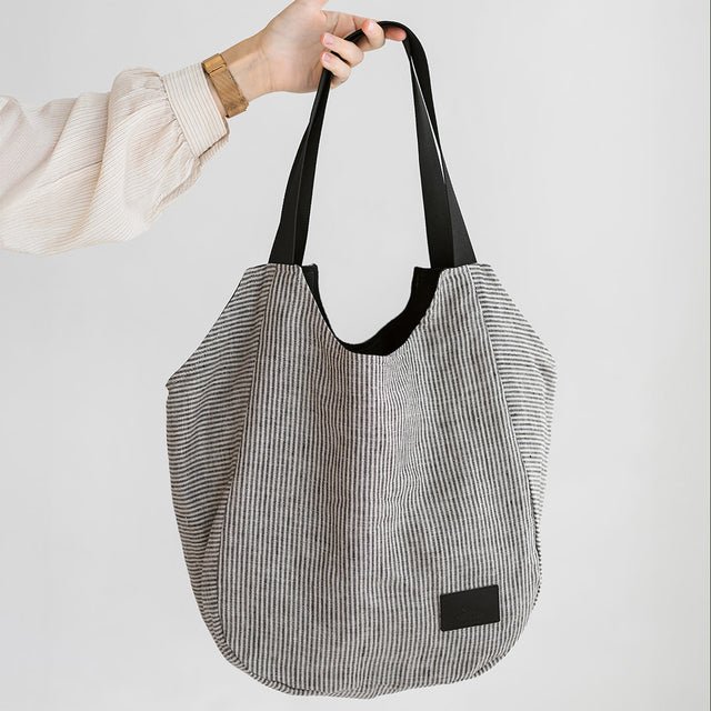 2. Muni striped linen tote bag held by a woman in a studio setting