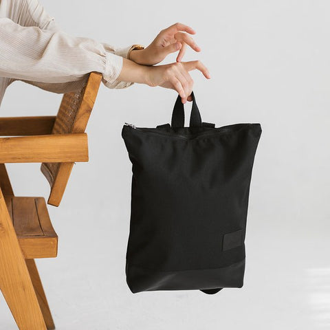 4. Muni black leather and polyester backpack held by woman, showing compact size and stylish look