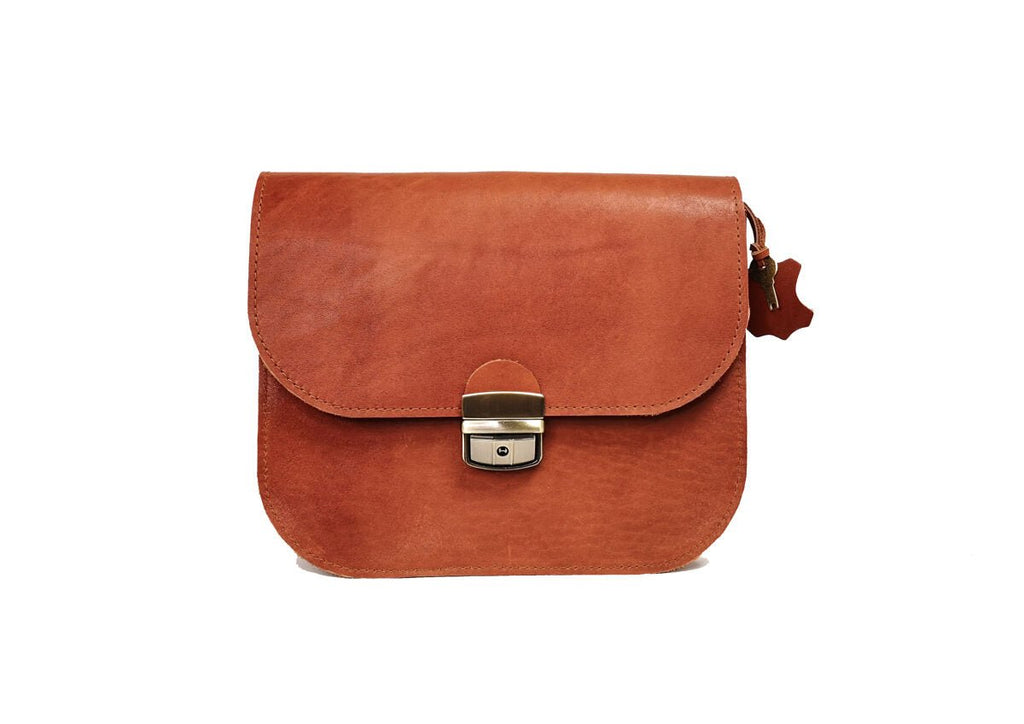 8. Front view of small Zelma Kraft natural leather saddle bag in light brown, studio setting with buckle closure
