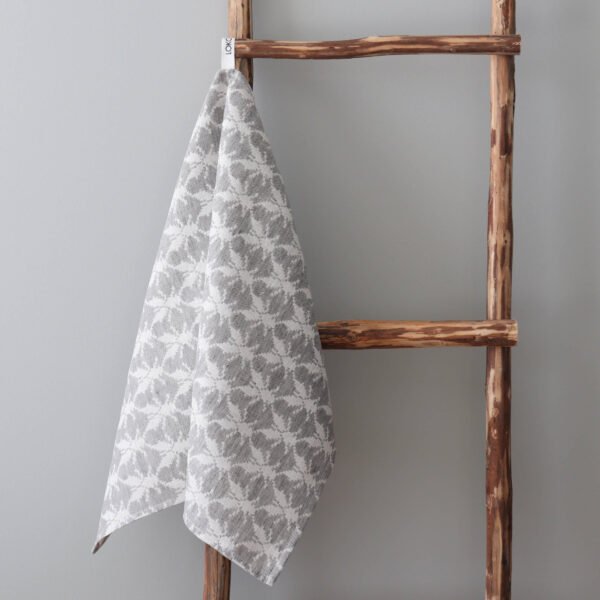 1. Grey and white kitchen towel with Hanikatsi fly pattern hanging on rustic wooden ladder against light grey wall