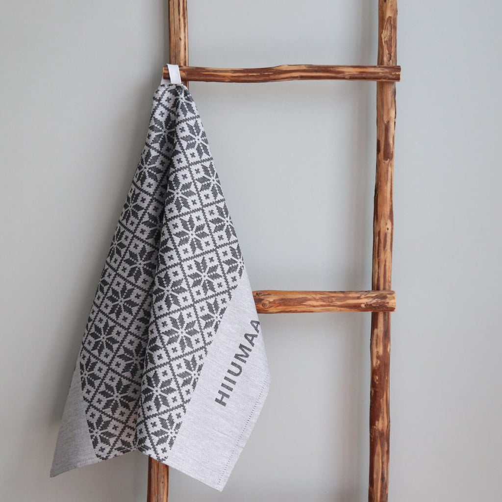 1. Grey kitchen towel with Pühalepa folk art pattern and Hiiumaa text hanging on wooden ladder