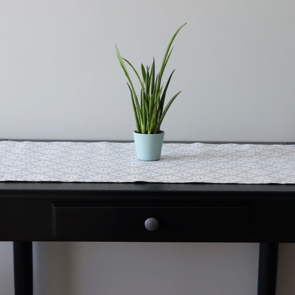 1. Table runner with Setumaa folk art pattern on black table with potted plant, 145 x 40 cm, linen-cotton blend
