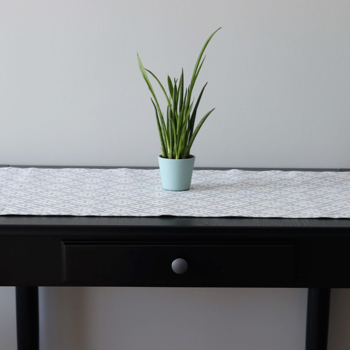 1. Table runner with Setumaa folk art pattern on black table with potted plant, 145 x 40 cm, linen-cotton blend